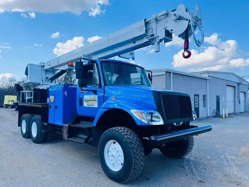 The blue Lamb Brothers crane truck, lettered with the company name and phone number