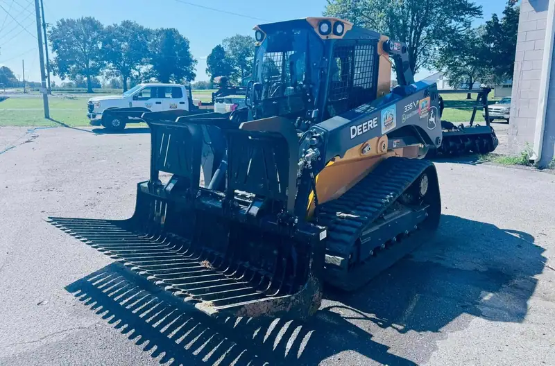 A John Deere track loader with a grapple rake