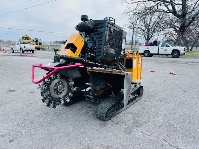 A tracked stump grinder with a pink guard cage