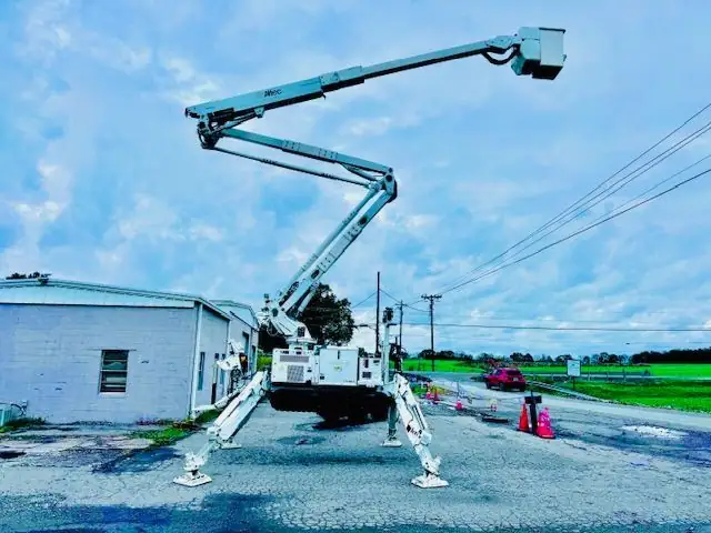 A white tracked spider lift with its boom fully extended